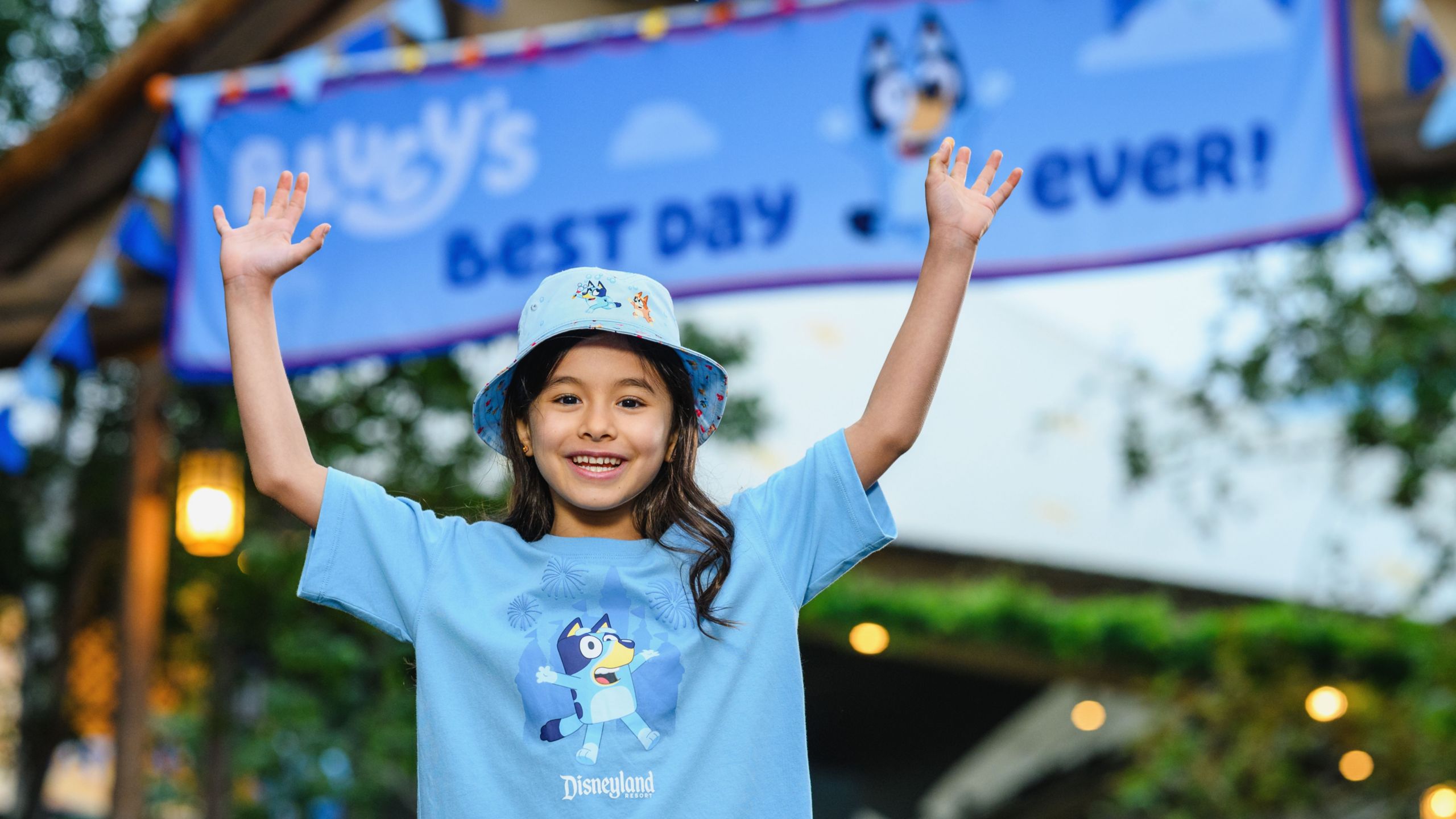 A young girl wearing a Bluey bucket hat and Disneyland Resort Bluey tee