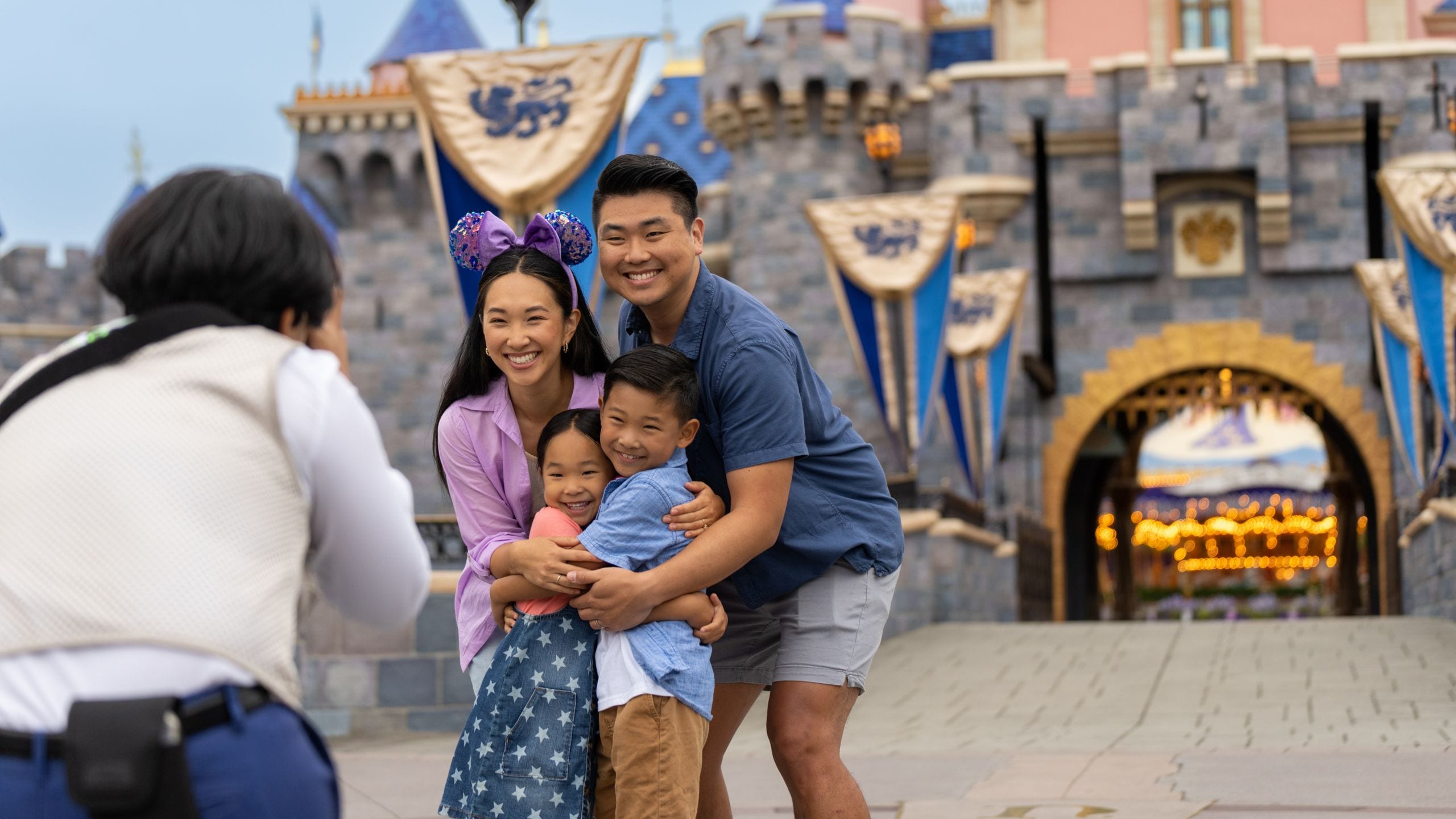 Un fotógrafo de Disney PhotoPass tomando una foto de una familia frente al castillo Sleeping Beauty Castle