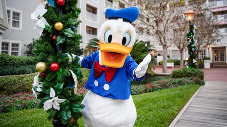 Donald Duck posing next to a lamp post with holiday garland at Disney's Yacht Club Resort