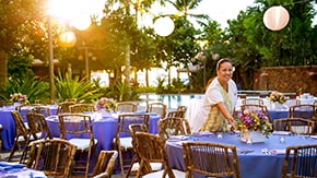 Disney Cast Member sets up outdoor dining tables with floral displays for a reception