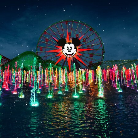 The World of Color, Season of Light nighttime holiday spectacular at Disney California Adventure Park, with many synchronized fountains spouting water and the Pixar Pal A Round Ferris wheel in the background
