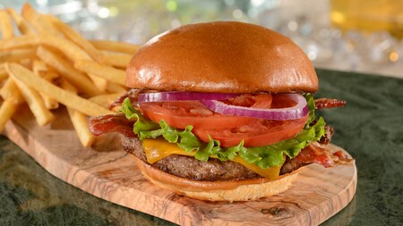 A cheeseburger with onion, tomato, lettuce and bacon, served with French fries