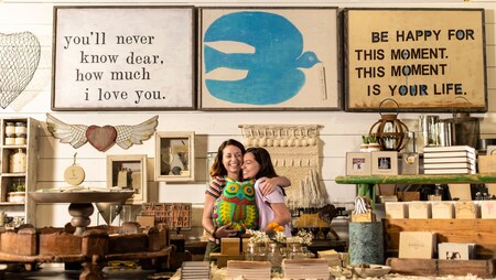 Amidst merchandise displays, a woman holding a stuffed owl shares hugs with her daughter