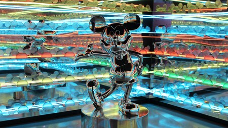 A metallic statue of Mickey Mouse in a room with mirrors and coloured lights