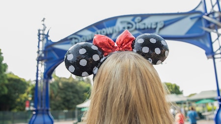 Guest wearing Mickey Ears in front of the Downtown Disney District entrance
