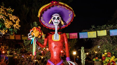 During Day of the Dead Celebrations at the Disneyland Resort is the iconic skeleton figurine La Catrina, the symbol of the Day of the Dead with brightly colored flowers and a decorative hat.