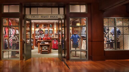Una tienda decorada con madera dura, un letrero que dice “Acorns Gifts & Goods” y mercancía que incluye playeras, bolsas y sombreros de Disney, además de sombreros con orejas de Mickey Mouse