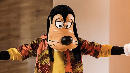 Goofy wearing a stylish sports coat and tie while holding his arms open in a welcoming manner