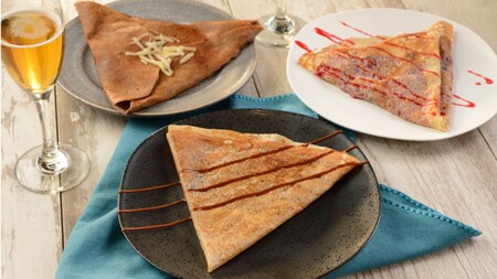 3 platos de crepes junto a una copa de vino espumoso