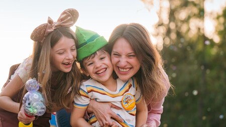 A woman and a girl embracing a young boy wearing a First Visit button