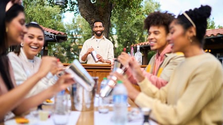 An instructor shows a group of seminar attendees how to mix a drink in a cocktail shaker