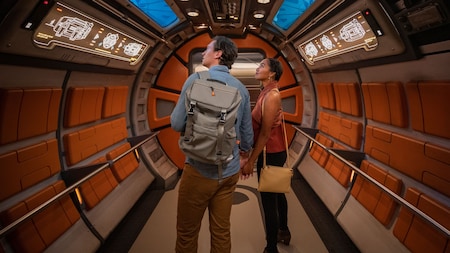 A couple explores a rounded corridor aboard the Halcyon starcruiser