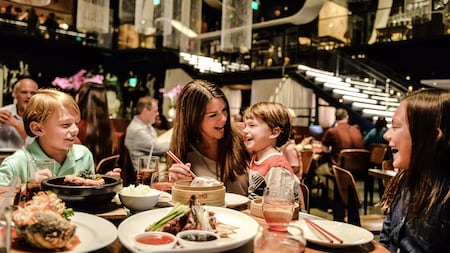 A mother and her 2 children smile while eating in a modern dining room at Morimoto Asia