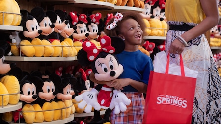 A child and mother in front of shelves featuring Minnie Mouse plushes at World of Disney in Disney Springs
