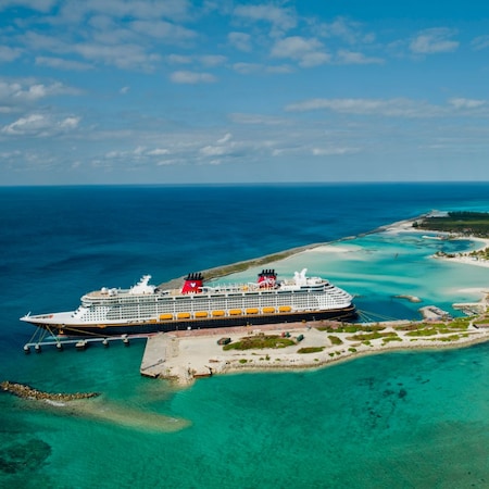 Um navio de cruzeiro da Disney atracado em uma ilha exuberante com praias de areia