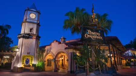  A clock tower and a pirate skeleton in a crows nest next to the Pirates of the Caribbean entrance