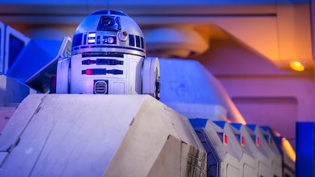 R2-D2 pops up from his position inside a craft within a dramatically lit room