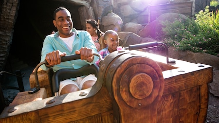 A family smiles while riding Seven Dwarfs Mine Train at Magic Kingdom park