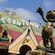 A statue of Mickey as a conductor with a Toontown sign in the hills behind him