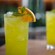 Cócteles luminiscentes preparados en vasos altos con hielo, adornados con menta y una rodaja de naranja