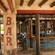 Pilares de madera sostienen el techo, y paneles y taburetes de acero alineados en el mostrador en un bar al aire libre