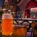 Close-up of a glass stein filled with beer and, in the background, a stage for entertainment