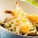 Bowl of udon noodles topped with 2 pieces of tempura shrimp