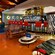Colorful seating area next to the bar, with tables, patio furniture, chairs, a lamp and TV sets