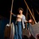 A young woman laughing while navigating between large swinging axe like pendulums in a darkened challenge room