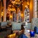 A dining room with arched ceilings, chandeliers, stained glass windows and tables set with napkins and glassware