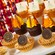 A tiered dessert plate with mini chocolate cupcakes decorated with icing, pretzel sticks and marshmallows to resemble campfires, alongside tarts topped with chocolate paw print medallions