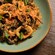 A ceramic bowl filled with squid ink pasta, calamari rings, mussels and baby octopus, topped with toasted breadcrumbs and basil leaves