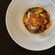 A seared fish fillet, surrounded by sauce and garnished with edible flowers and microgreens
