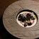 A bowl of panna cotta swirled with berry sauce, meringue pieces, chocolate crumble, whole cherries and sliced kumquats