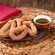 A plate of cinnamon sugar Churro Loops served with a cup of chocolate dipping sauce on a woven placemat