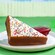 Slice of Fairy Bread Cake dipped in white chocolate and rainbow sprinkles with a side of raspberry sauce