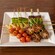 Un plato de carnes y vegetales fritos y en brochetas