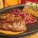 A grilled pork chop with garlic crust on a plate served with cabbage and carrot slaw and corn cake at Tiffins Restaurant