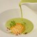 A carafe pouring soup into a bowl containing microgreens and an edible honeycomb structure