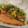A plate with a fish filet and an assortment of vegetables on the side