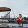 A mother observes as her daughter casts a line with a lure over the side of a boat