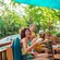 A Cast Member taking drink orders from 3 laughing Guests on a shaded deck at Disney’s Blizzard Beach water park