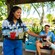 A Cast Member serving tropical drinks to a family relaxing in a shaded beach cabana at Disney’s Typhoon Lagoon water park