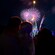 A crowd watching fireworks burst above Cinderella Castle at Magic Kingdom park