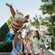 Two children sitting with their mother beneath a large statue of Santa Claus on a surfboard at Winter Summerland Miniature Golf