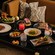 A table with dishes of steak, beef, paella, bone marrow, vegetable sides, fried bites and cocktails