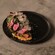 Greens and thinly sliced beets on top of a grain base on a plate