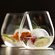 Two stemless glasses filled with cocktails and garnished with lime, berries, rosemary and ice