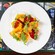 A burrata salad featuring burrata topped with heirloom tomatoes, stone fruit, arugula leaves and dressing