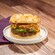 A beef burger with jalapeno cheese sauce, crispy onions and other ingredients on an onion roll